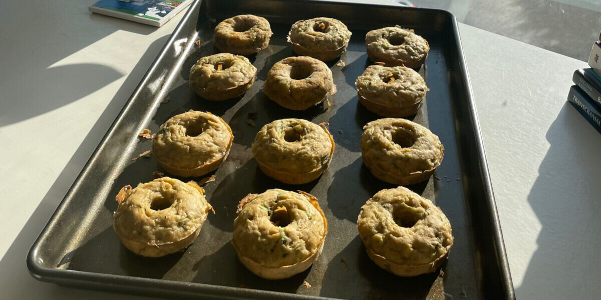 Pan of zucchini donuts on desk in front of window